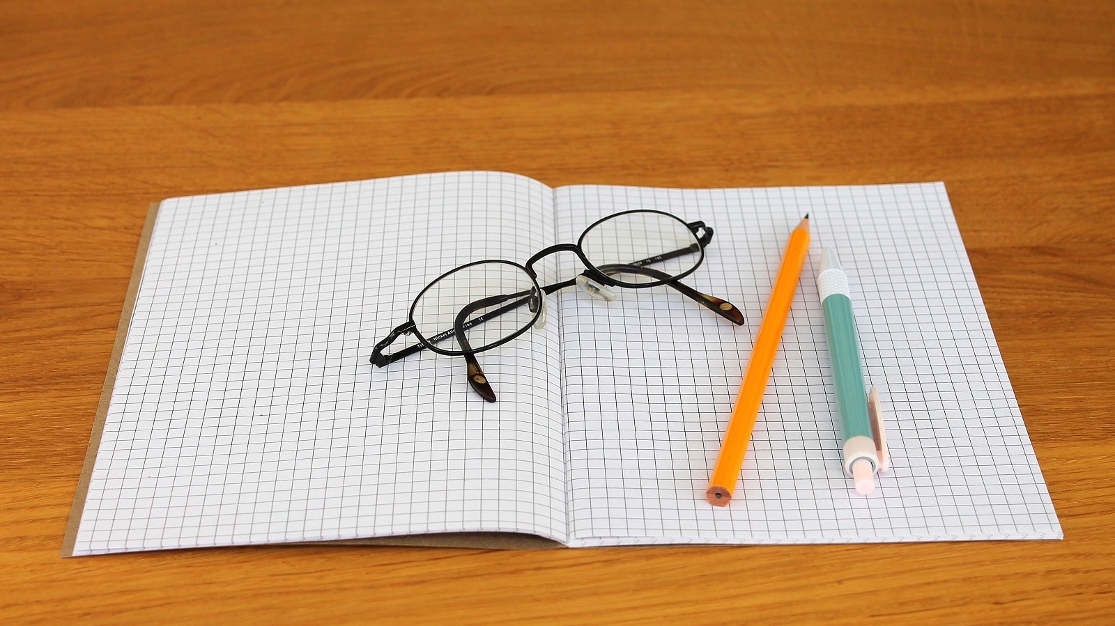 Glasses on graph paper with pencil and pen