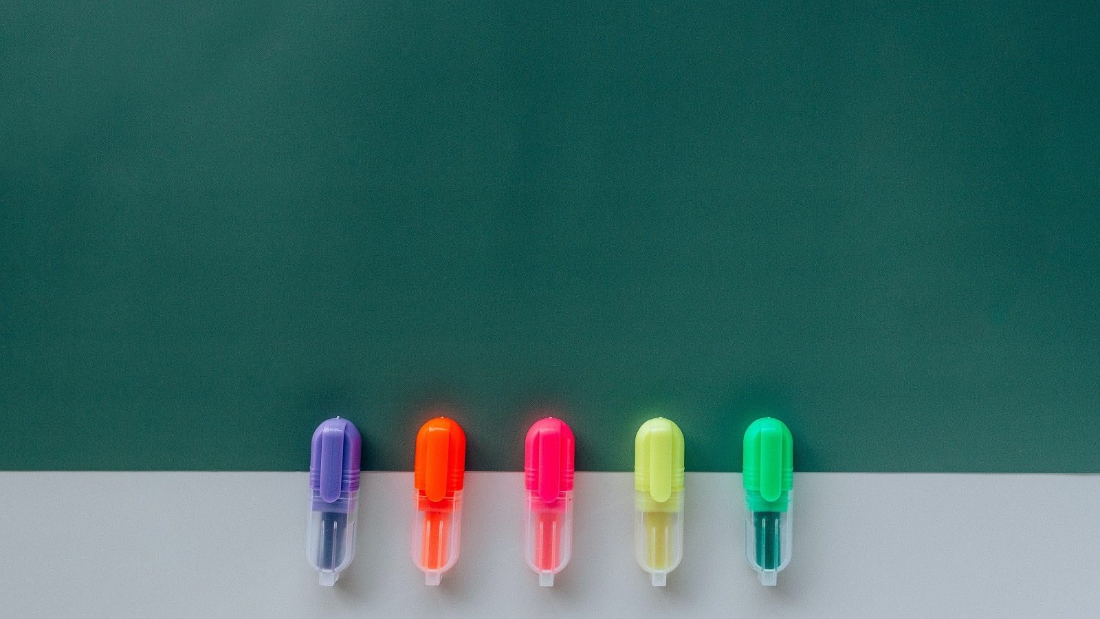 Highlighters in a row on a dark green background