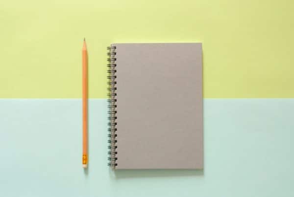 Closed notebook with pencil on green and blue background