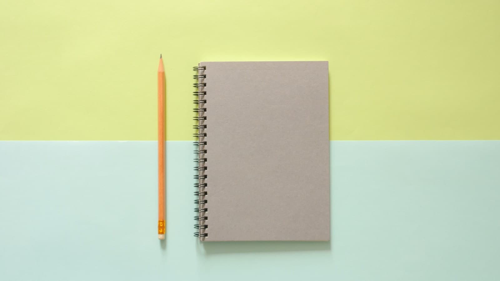 Closed notebook with pencil on green and blue background