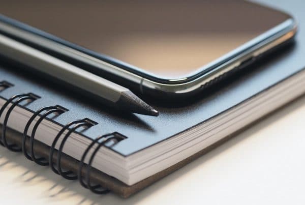 Phone on top of blue notebook with black pencil