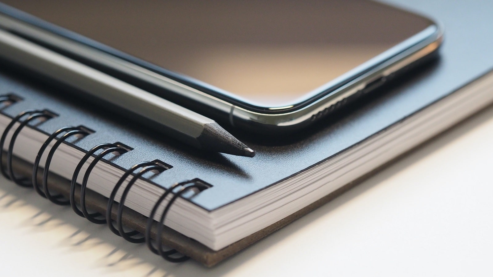 Phone on top of blue notebook with black pencil
