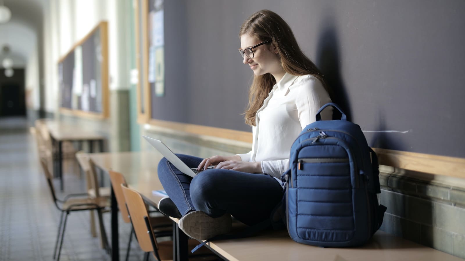 Girl on laptop with blue backpack