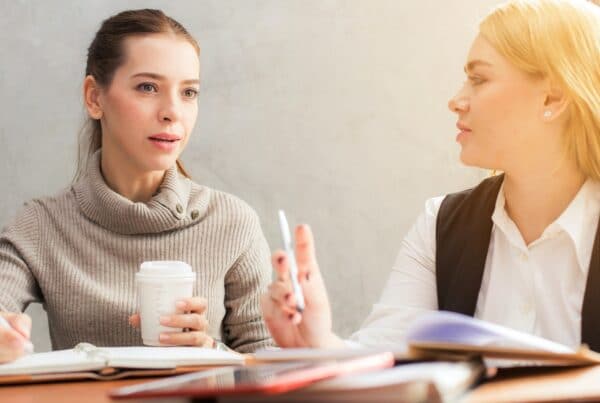 Two women at a desk studying and talking