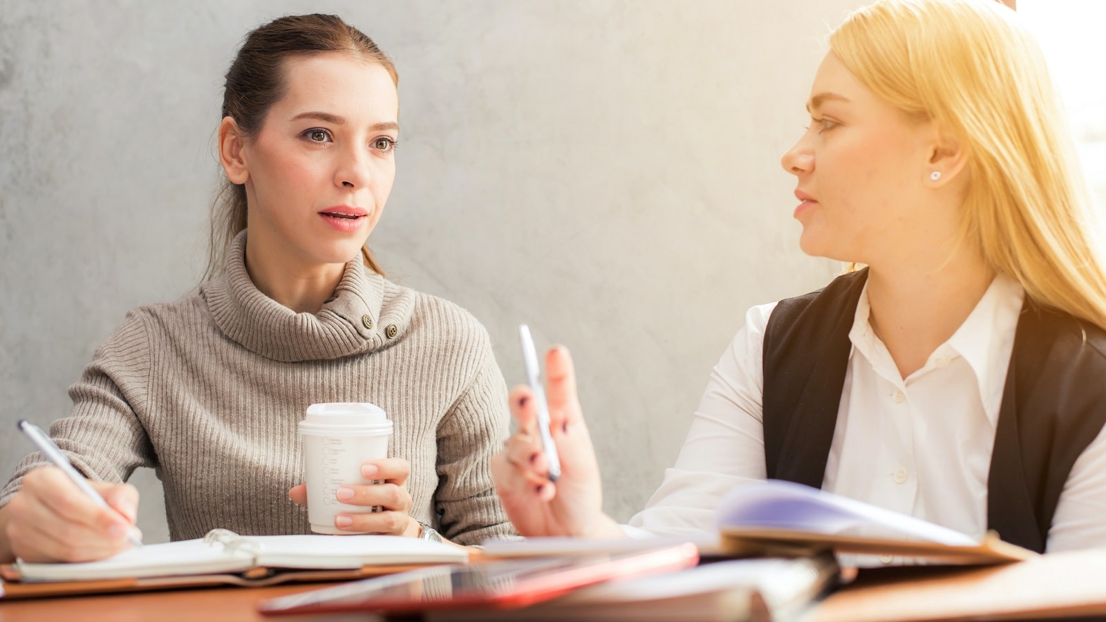 Two women at a desk studying and talking