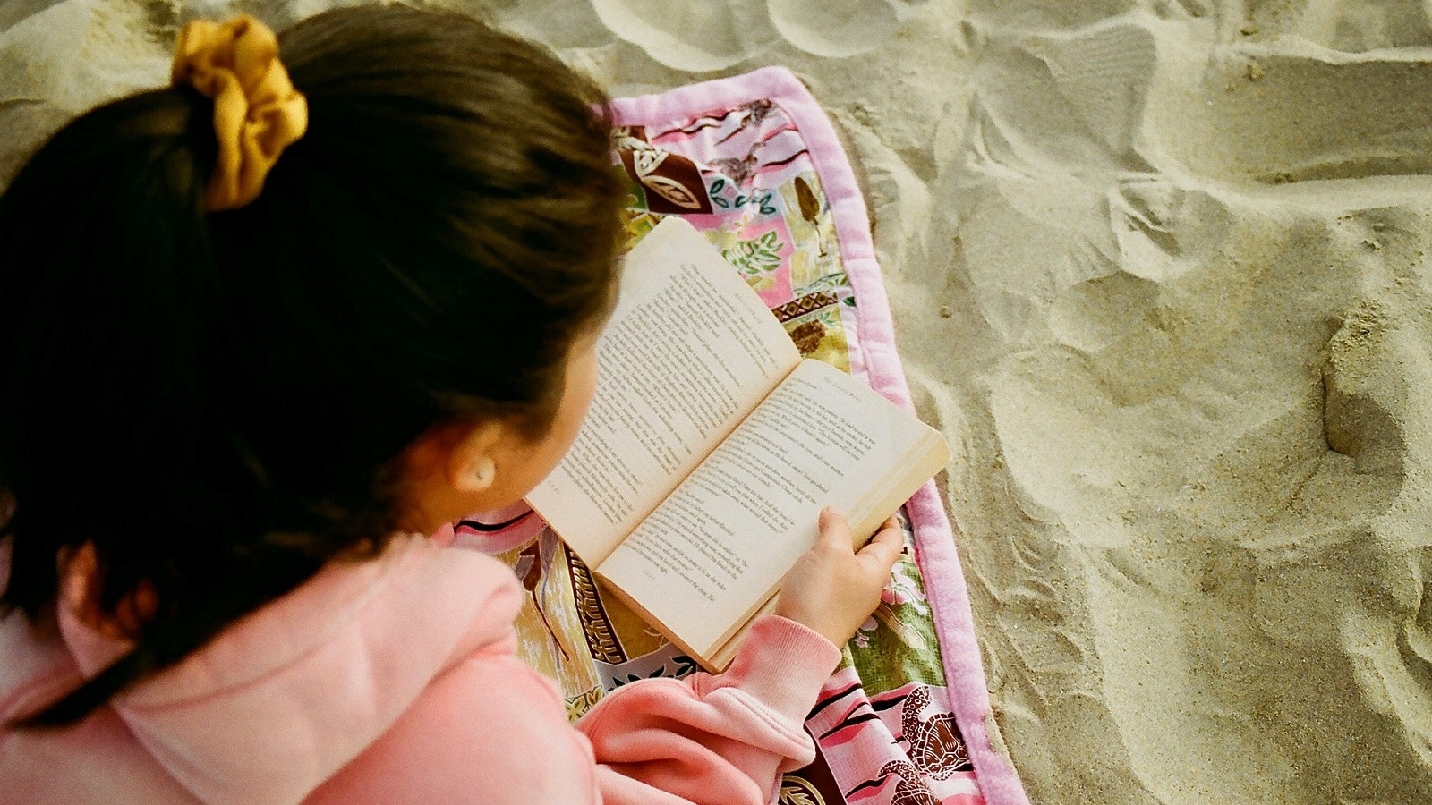 Girl reading a book in the sand