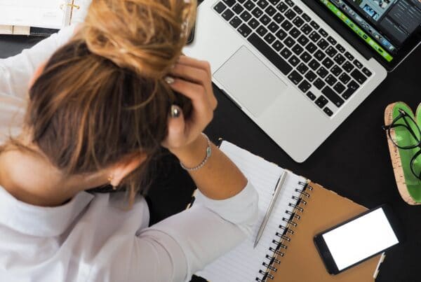 Stressed out student, hands on head over laptop