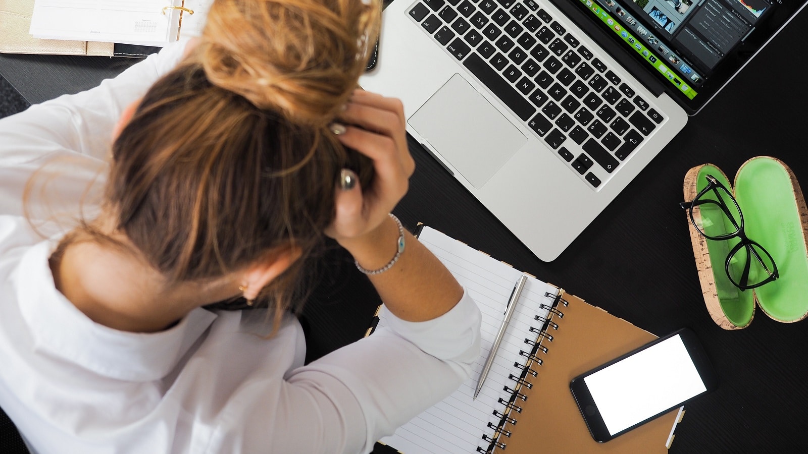 Stressed out student, hands on head over laptop