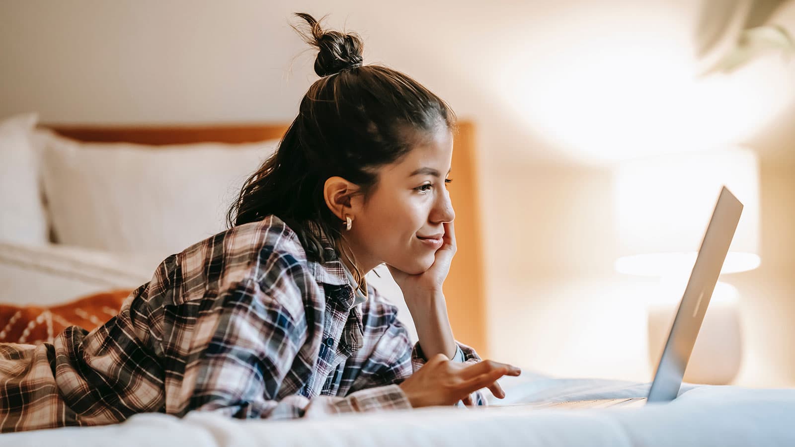 Student lying on bed on laptop