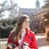 Woman in Red Coat Holding Notebooks and Coffee cup