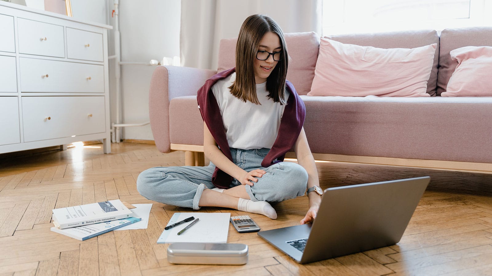 A young woman sitting on the floor while taking an online class