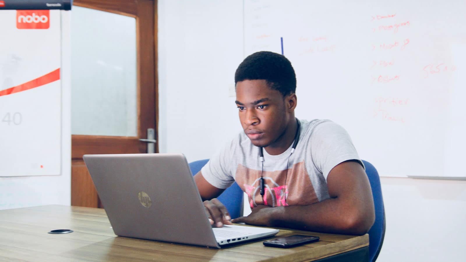 Student in grey shirt looking at laptop