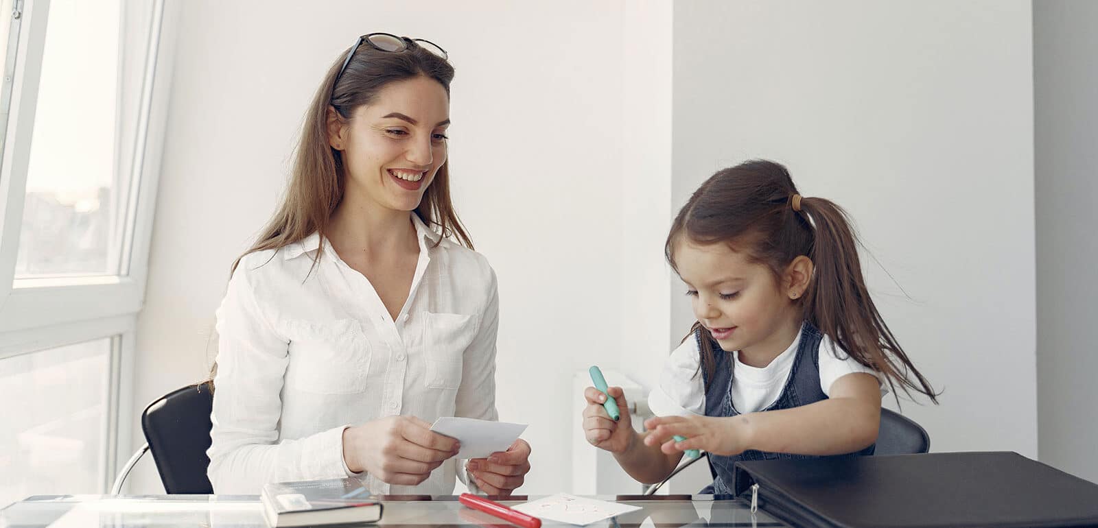 Happy mother and daughter studying in office