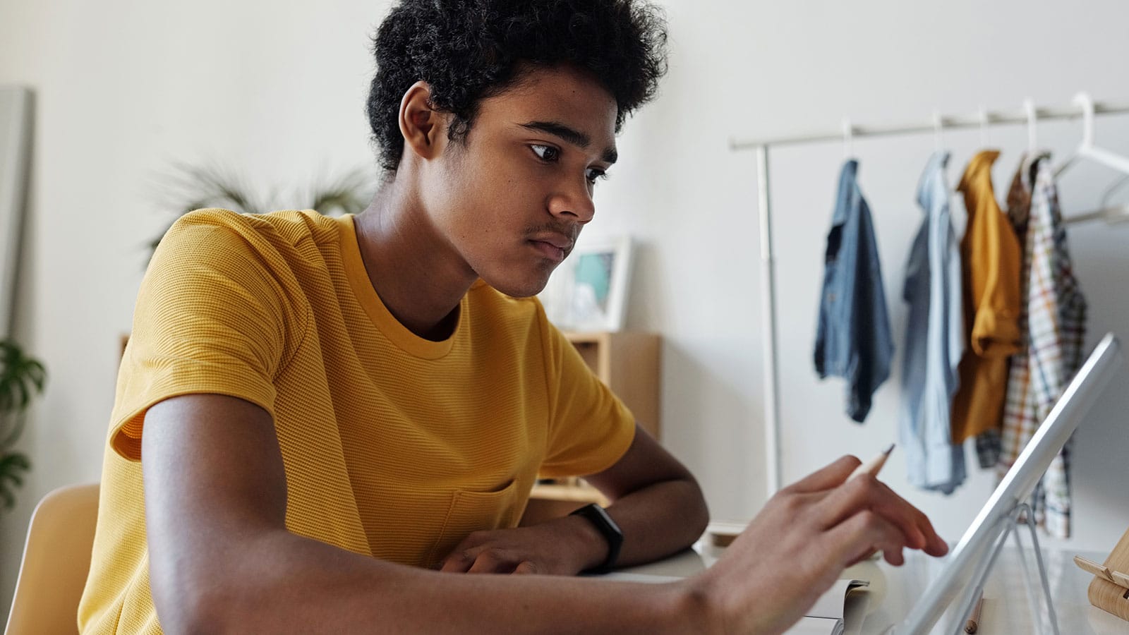 Student sitting and tapping on a tablet