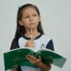 Girl holding a workbook with a pencil in her hand