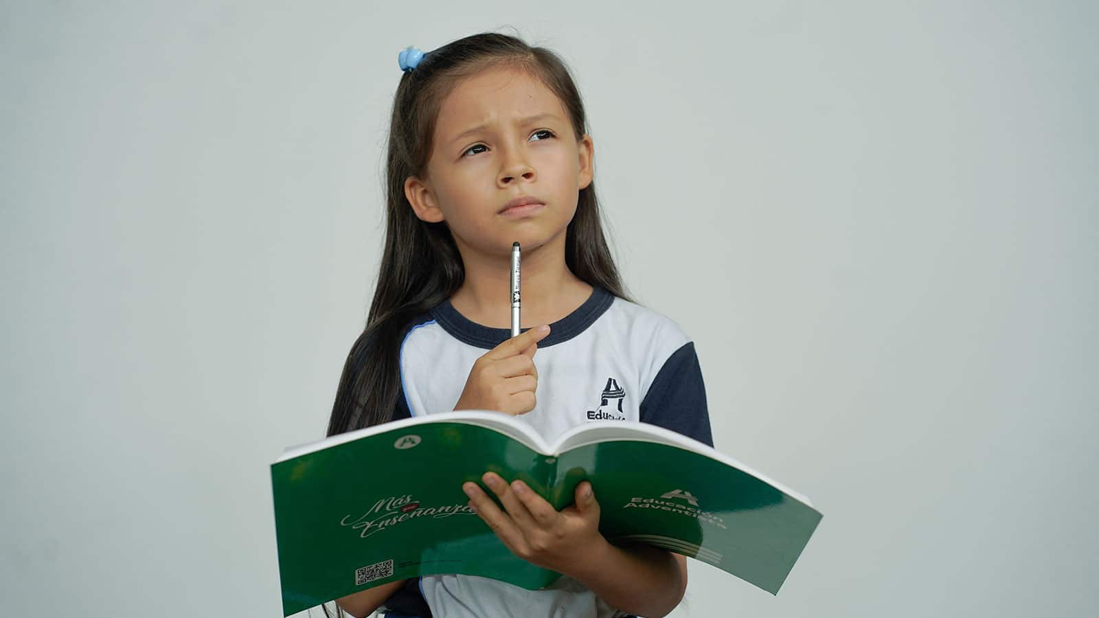 Girl holding a workbook with a pencil in her hand