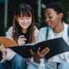 Two girls looking at each other's notebooks
