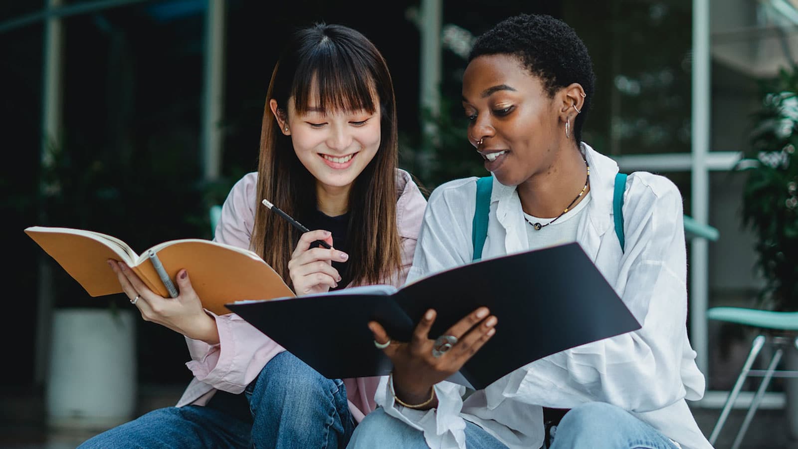 Two girls looking at each other's notebooks