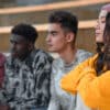Four young high school kids staring in the distance while sitting on school steps
