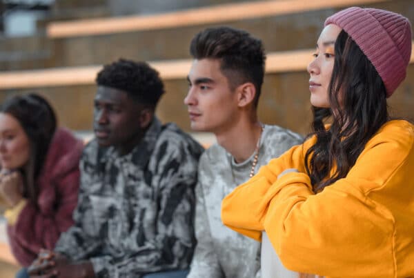 Four young high school kids staring in the distance while sitting on school steps