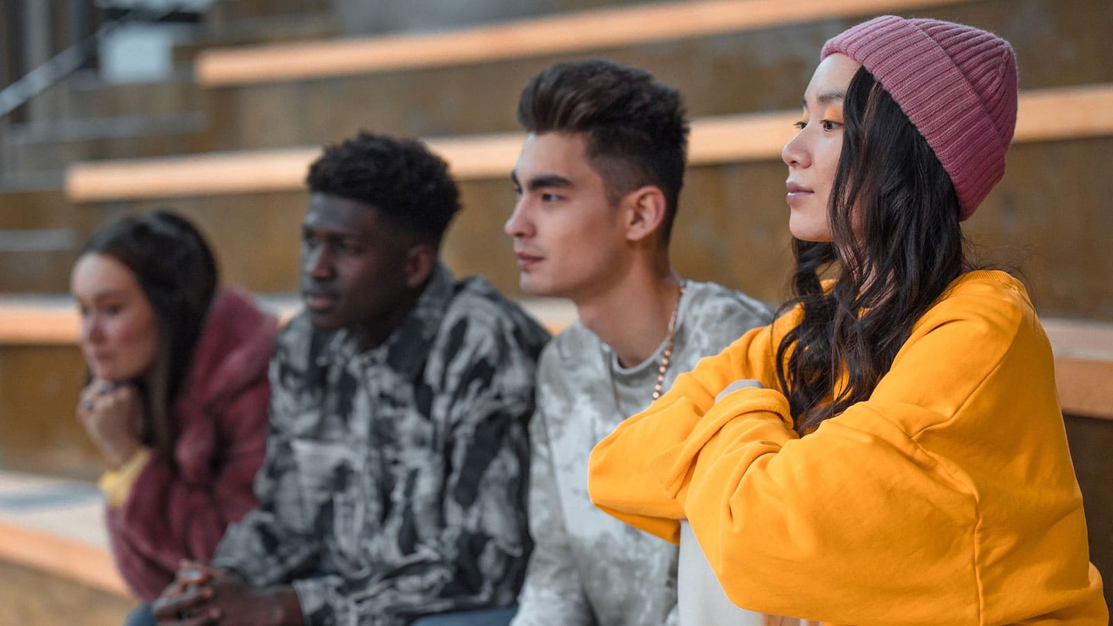 Four young high school kids staring in the distance while sitting on school steps