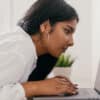 Young girl leaning over a desk staring at a laptop screen