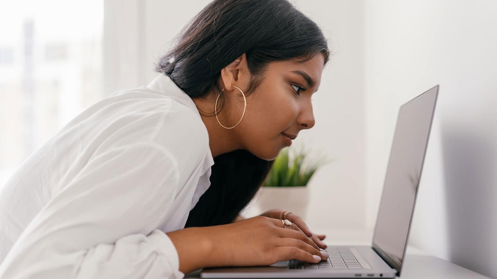 Young girl leaning over a desk staring at a laptop screen