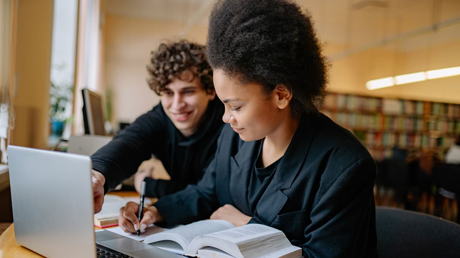 Man and Woman Studying while Writing on a Notebook