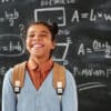 Smiling student wearing a backpack in front of a chalkboard with math equations on it