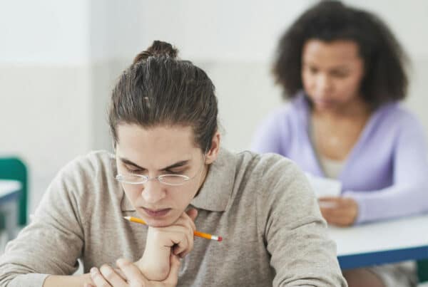 Two students sitting at a desk looking down at their papers while taking a test