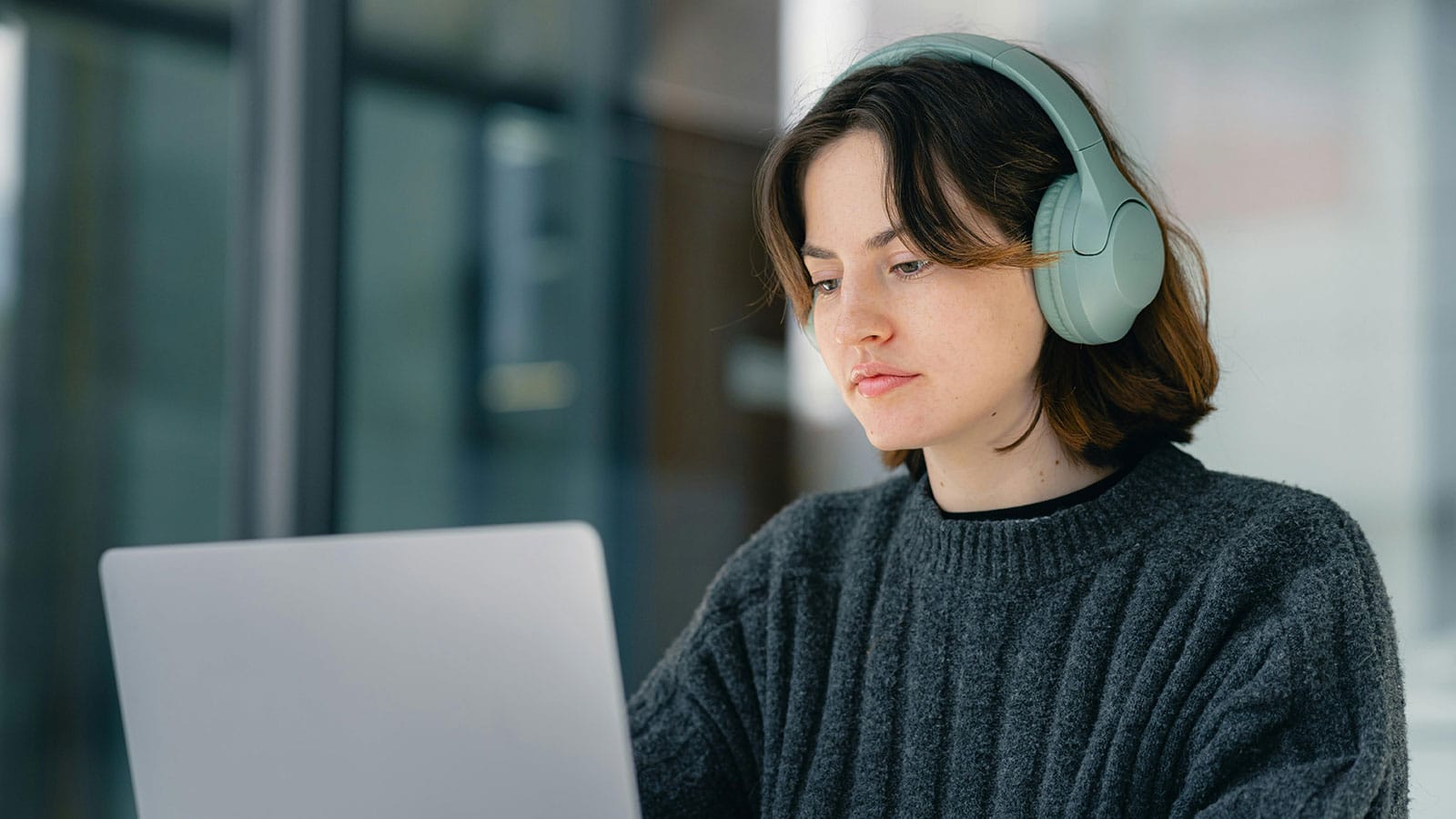 Student wearing headphones staring at a laptop screen