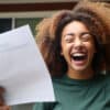 Ecstatic high school girl with eyes closed holding up a college acceptance letter