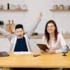 A young woman helps a boy with his lessons using a tablet and a globe
