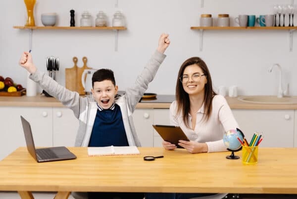 A young woman helps a boy with his lessons using a tablet and a globe