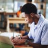 Student in a library taking a test with a digital device