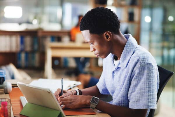 Student in a library taking a test with a digital device
