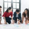 Five students kneeling on the floor with charts and worksheets in front of them