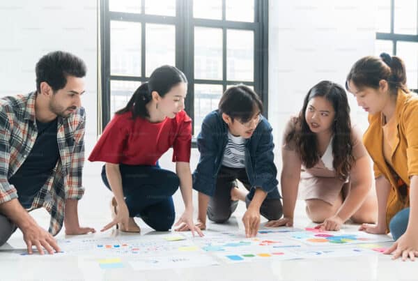 Five students kneeling on the floor with charts and worksheets in front of them