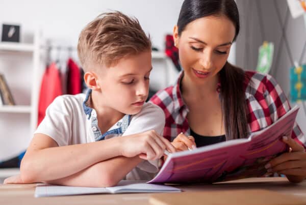 Image of a mom with her teen son both staring at a homework while sitting at a desk