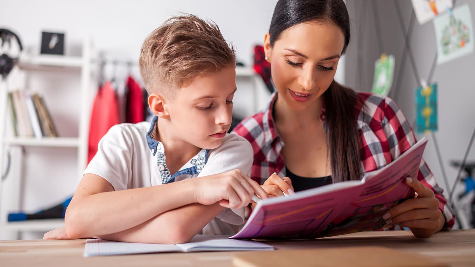 Image of a mom with her teen son both staring at a homework while sitting at a desk