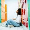 Teen girl sitting alone on the floor by school lockers feeling stressed